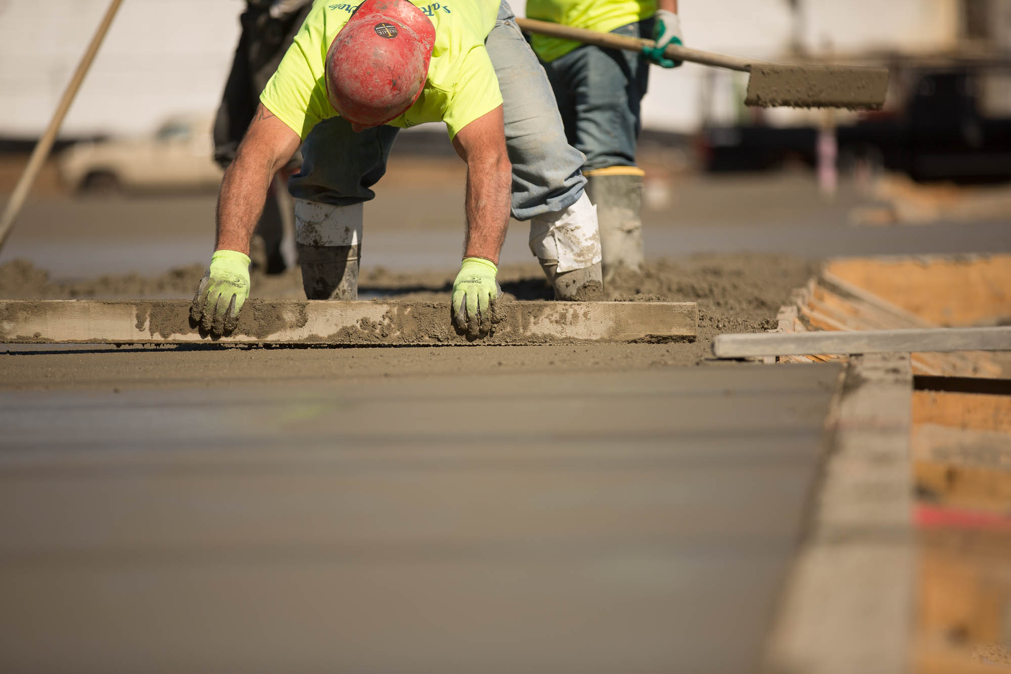 A man smoothing concrete with a board outside